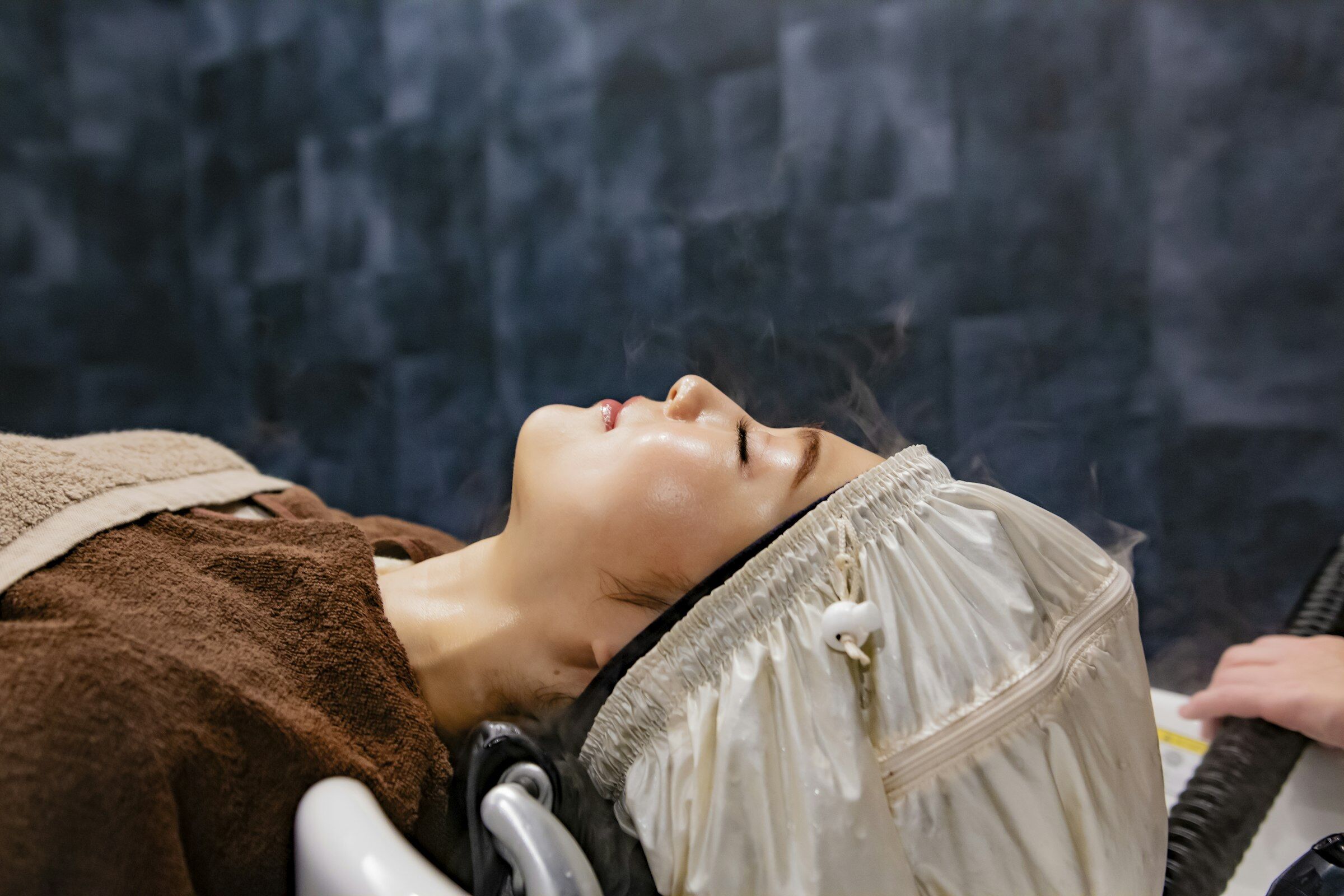 Guest relaxing under a warm steam facial, resting on soft towels
