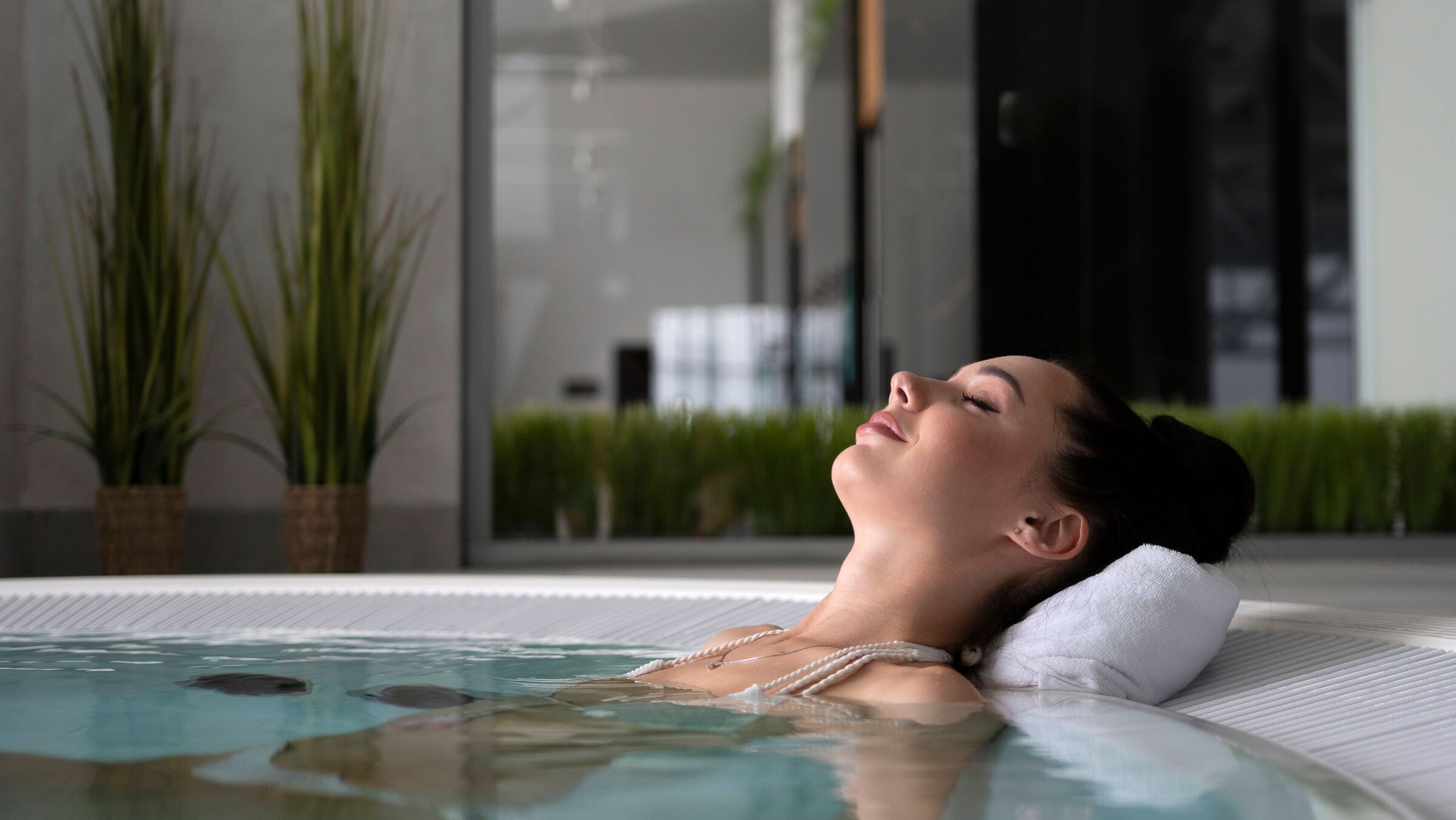 Woman relaxing with eyes closed in a warm spa pool